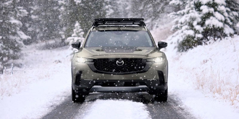 front view of a Mazda CX-50 driving off-road thru snow