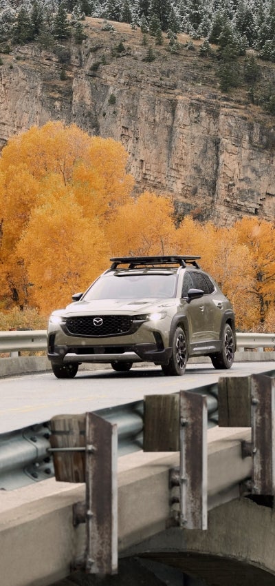 Front view of a Mazda CX-50 driving over a small bridge