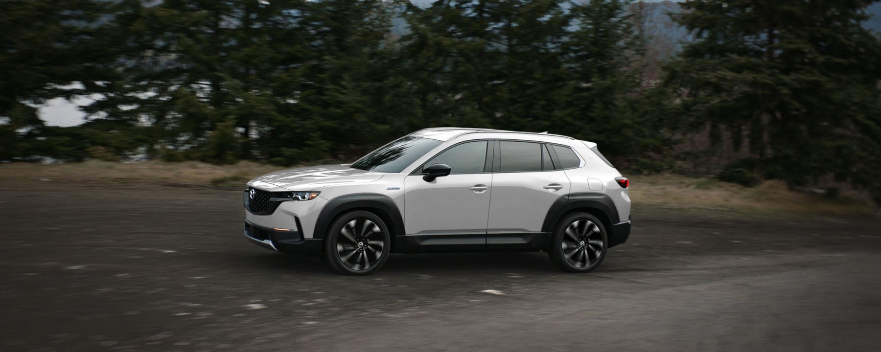 front side view of a 2024 Mazda CX-50 in silver parked on a country road