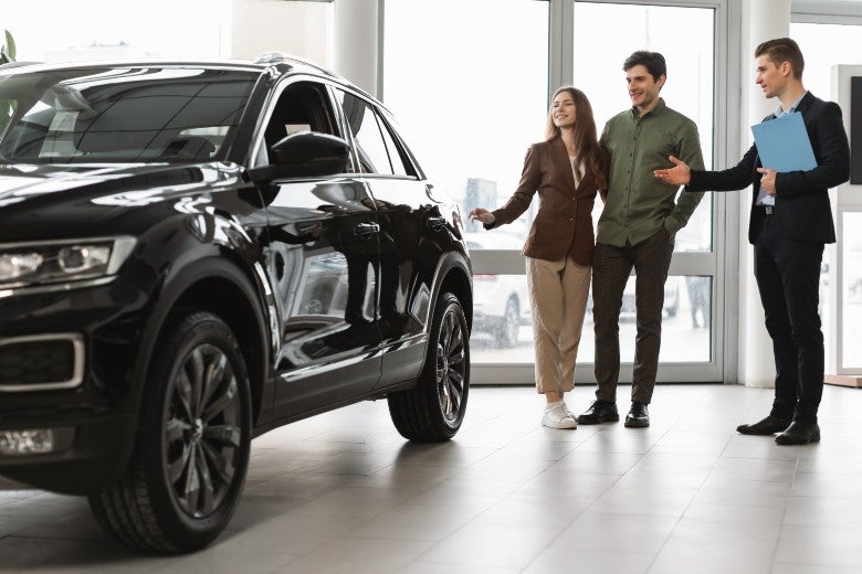 Couple Looking at a Used Car with a Salesman